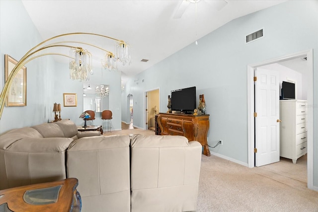 living room featuring ceiling fan with notable chandelier, vaulted ceiling, and light colored carpet