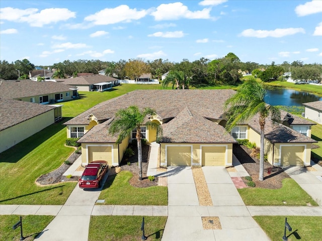 view of front facade with a front yard, a garage, and a water view