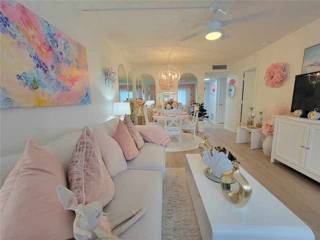 living room with ceiling fan with notable chandelier and light hardwood / wood-style flooring