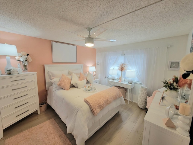 bedroom featuring ceiling fan, hardwood / wood-style flooring, and a textured ceiling