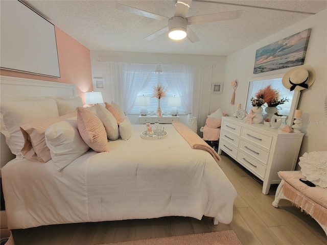 bedroom featuring light hardwood / wood-style floors, ceiling fan, and a textured ceiling