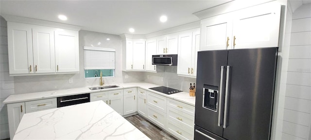 kitchen with appliances with stainless steel finishes, white cabinetry, light stone countertops, dark hardwood / wood-style floors, and sink