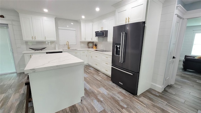 kitchen with light hardwood / wood-style floors, sink, white cabinets, a kitchen island, and black appliances