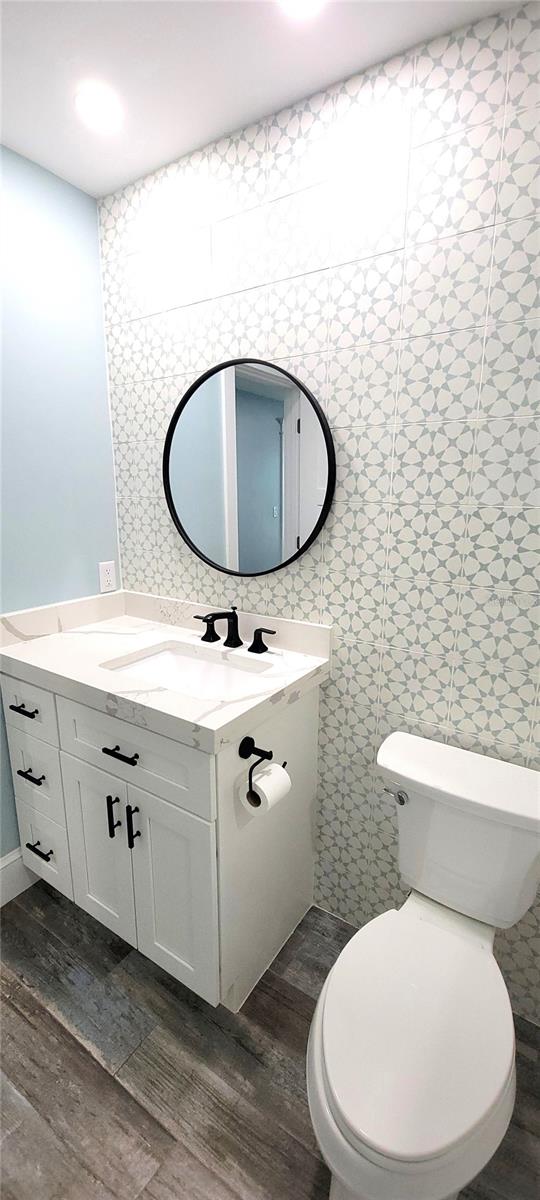 bathroom featuring tile walls, vanity, toilet, and hardwood / wood-style flooring