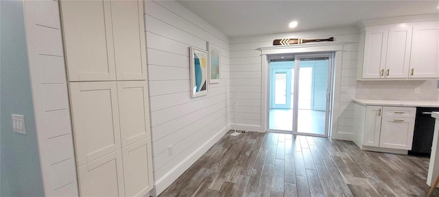 kitchen with wood-type flooring, white cabinetry, and wood walls