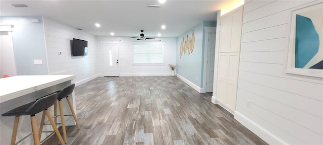 interior space featuring wood walls, dark wood-type flooring, and ceiling fan