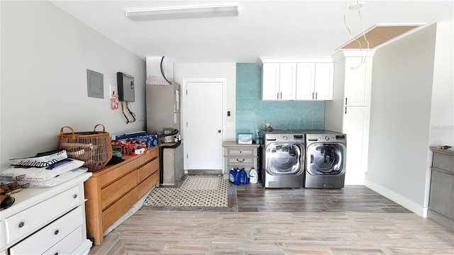 clothes washing area with cabinets, light hardwood / wood-style floors, electric panel, and washer and dryer