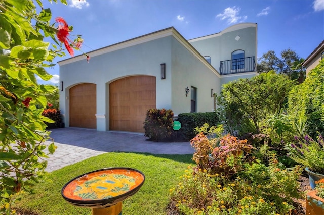 view of front of house featuring a front yard, a balcony, and a garage