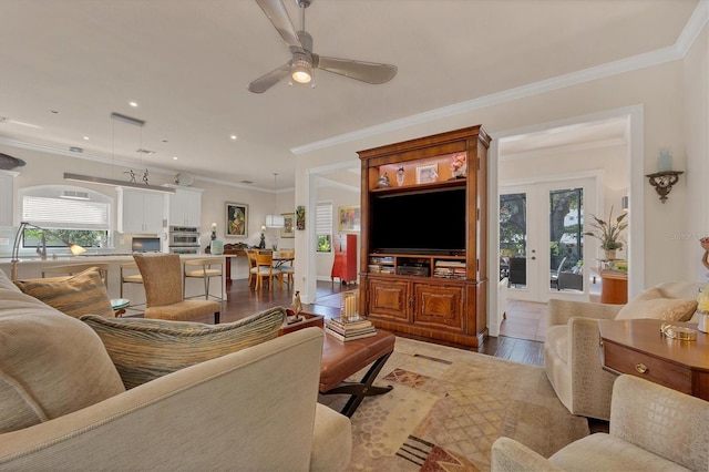 living room featuring crown molding, wood-type flooring, and ceiling fan