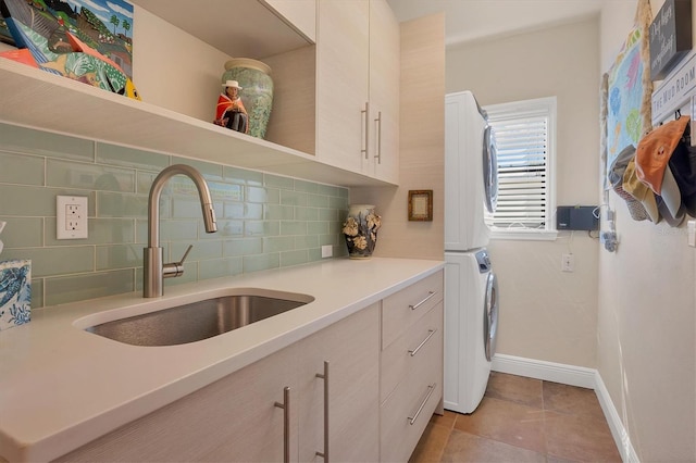 kitchen featuring sink, stacked washer and clothes dryer, backsplash, and light tile patterned floors