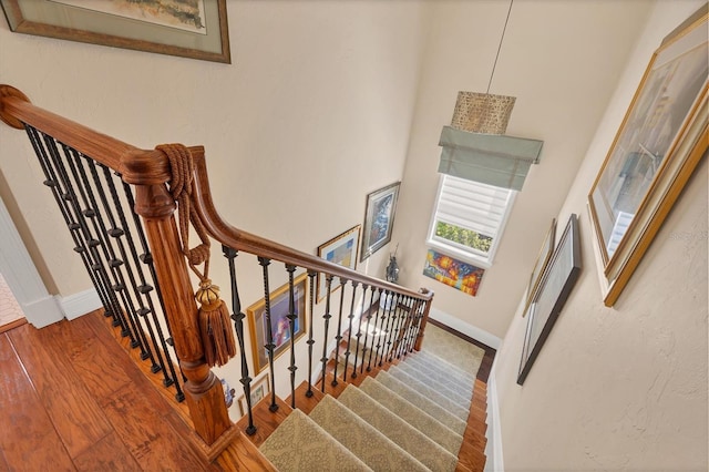 stairs featuring hardwood / wood-style flooring and a towering ceiling