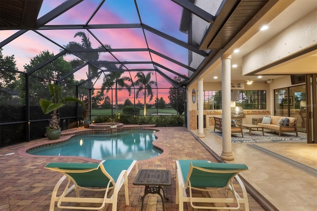 pool at dusk with a pool with connected hot tub, a patio, a grill, outdoor lounge area, and an outdoor kitchen