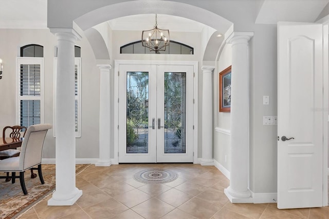 tiled entrance foyer featuring crown molding, a chandelier, and french doors