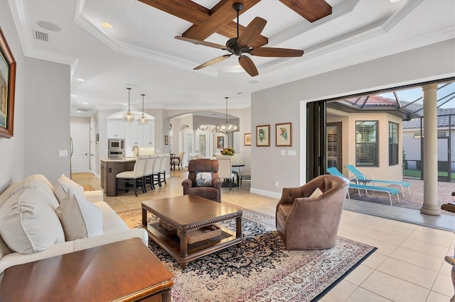 living room featuring ceiling fan with notable chandelier, ornamental molding, light tile patterned floors, and a raised ceiling