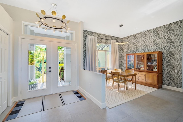 foyer with tile patterned flooring, a chandelier, plenty of natural light, and french doors