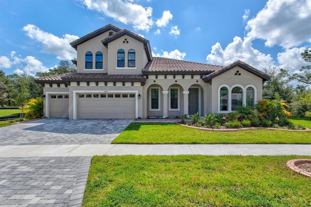 mediterranean / spanish home featuring a garage and a front yard