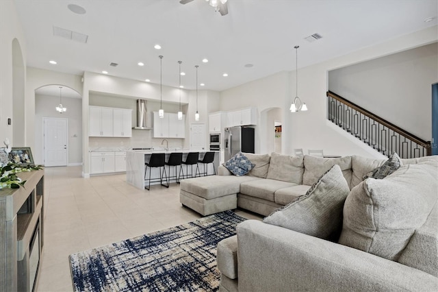 tiled living room featuring ceiling fan with notable chandelier