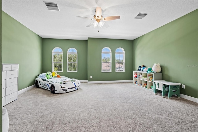 bedroom with ceiling fan, a textured ceiling, carpet, and multiple windows