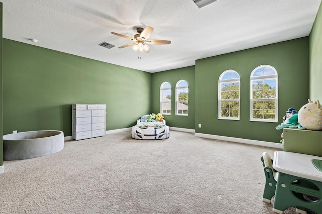 game room with a textured ceiling, ceiling fan, and carpet floors