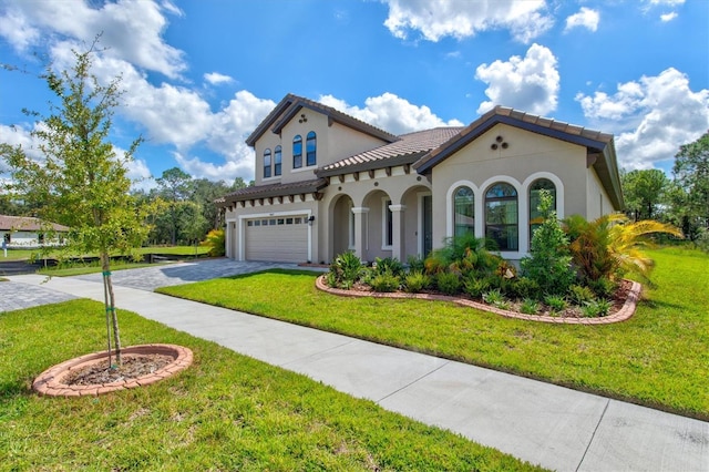 mediterranean / spanish house with a garage and a front lawn