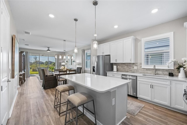 kitchen with white cabinets, light hardwood / wood-style floors, sink, and stainless steel appliances