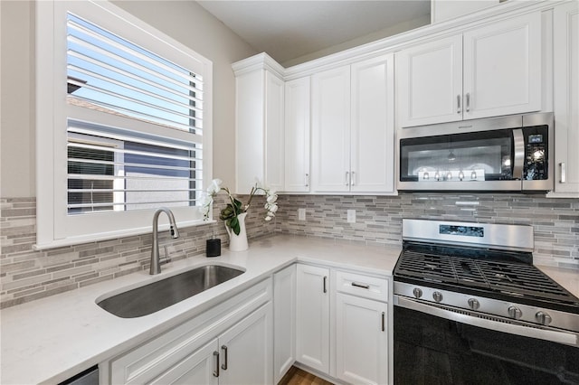 kitchen with sink, white cabinets, decorative backsplash, and appliances with stainless steel finishes