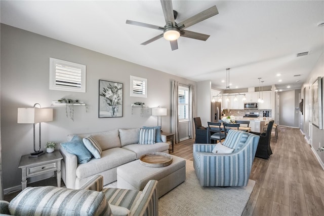 living room with ceiling fan and light wood-type flooring