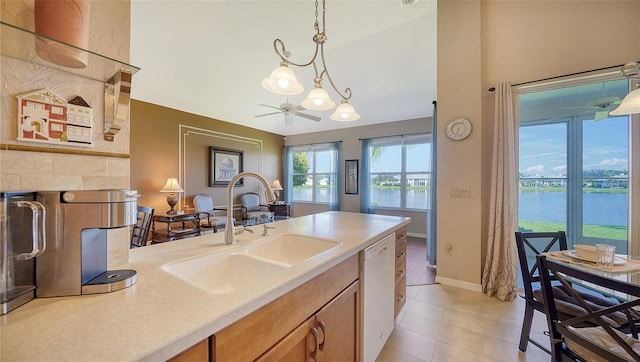 kitchen with dishwasher, a water view, sink, ceiling fan, and decorative light fixtures