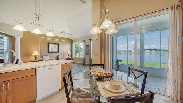 dining space with sink, light tile patterned flooring, decorative columns, vaulted ceiling, and a water view