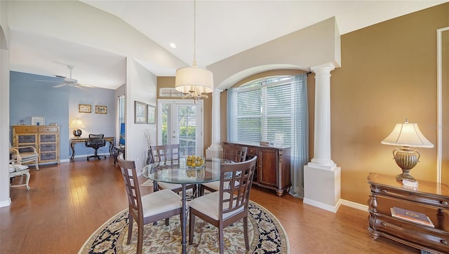 dining space with ceiling fan with notable chandelier, wood-type flooring, lofted ceiling, and ornate columns