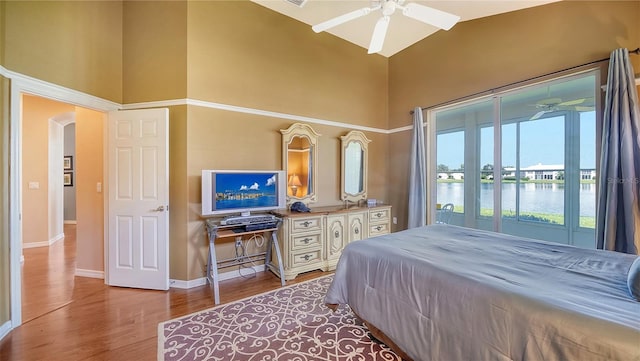 bedroom featuring ceiling fan, light hardwood / wood-style flooring, and a towering ceiling