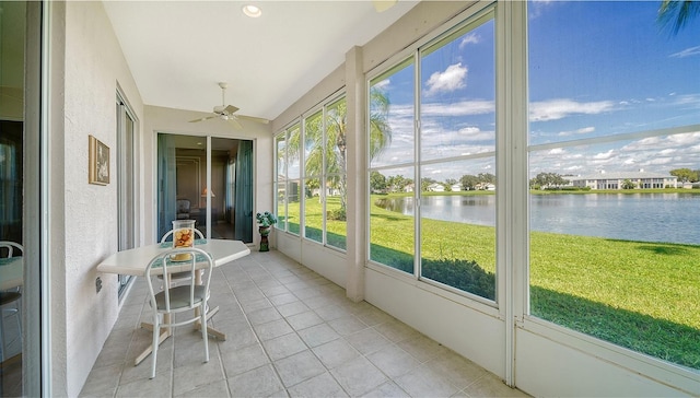 unfurnished sunroom with ceiling fan and a water view