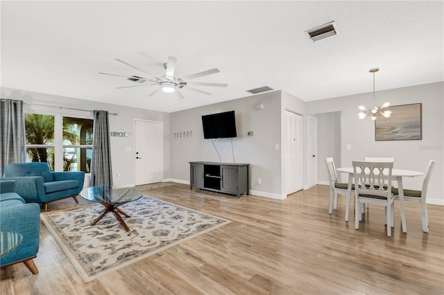 living room featuring ceiling fan with notable chandelier and light hardwood / wood-style flooring