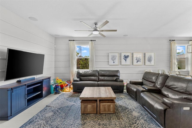 living room featuring ceiling fan, wood walls, and light tile patterned floors