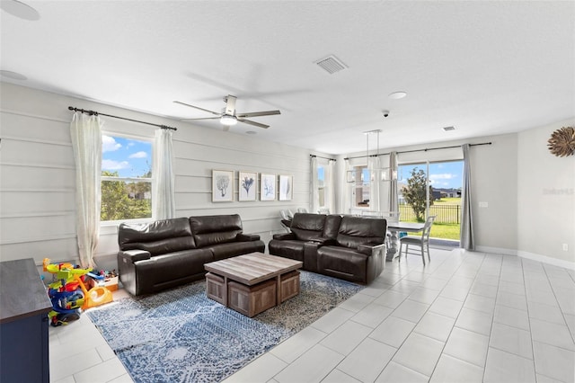 living room featuring light tile patterned flooring, ceiling fan, and a textured ceiling