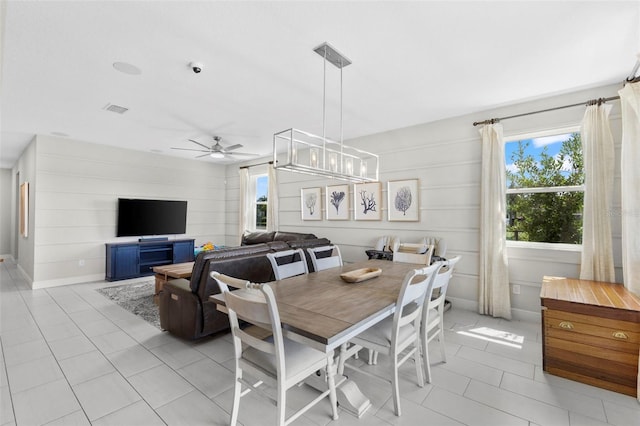 tiled dining room featuring wood walls and ceiling fan