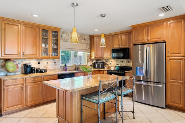 kitchen featuring pendant lighting, sink, a kitchen island, black appliances, and light stone countertops