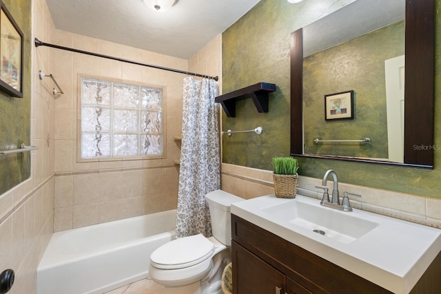 full bathroom with tile walls, a textured ceiling, shower / tub combo with curtain, vanity, and toilet