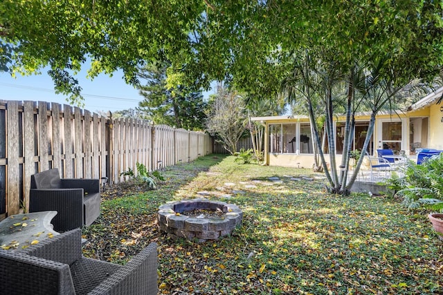 view of yard featuring a sunroom, a patio area, and a fire pit