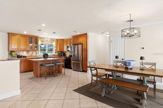 kitchen featuring pendant lighting, stainless steel fridge, a breakfast bar, backsplash, and a kitchen island