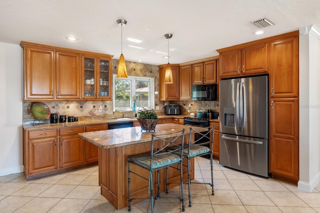 kitchen with pendant lighting, a breakfast bar area, a center island, light stone counters, and black appliances