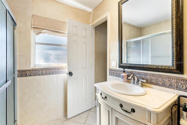 bathroom with vanity, a shower with door, tile patterned floors, and tile walls