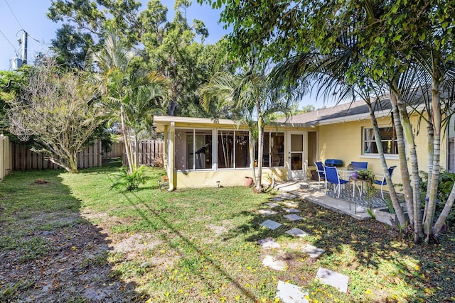 back of property featuring a yard, a sunroom, and a patio