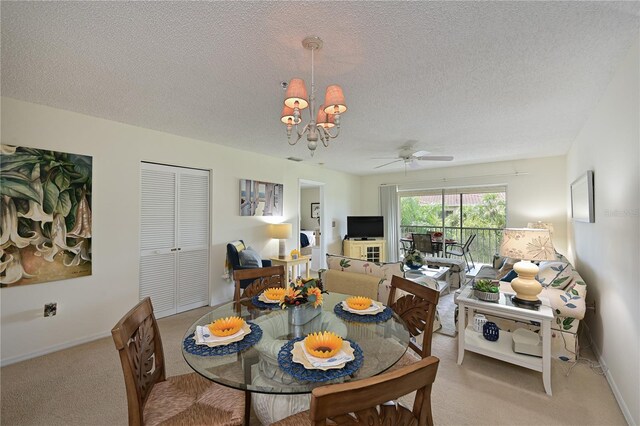 dining room with a textured ceiling, ceiling fan with notable chandelier, baseboards, and light colored carpet