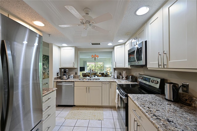 kitchen featuring white cabinetry, ceiling fan, light tile patterned floors, a tray ceiling, and appliances with stainless steel finishes