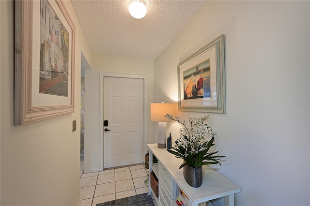 doorway to outside featuring light tile patterned floors and a textured ceiling