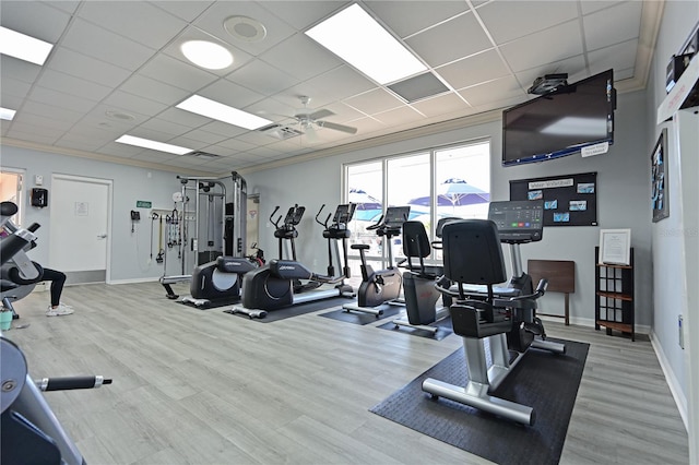 exercise room featuring baseboards, ornamental molding, and wood finished floors