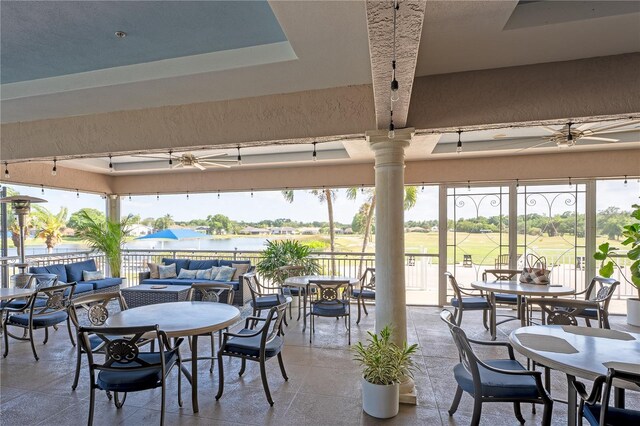 dining area featuring ceiling fan, a tray ceiling, and a water view