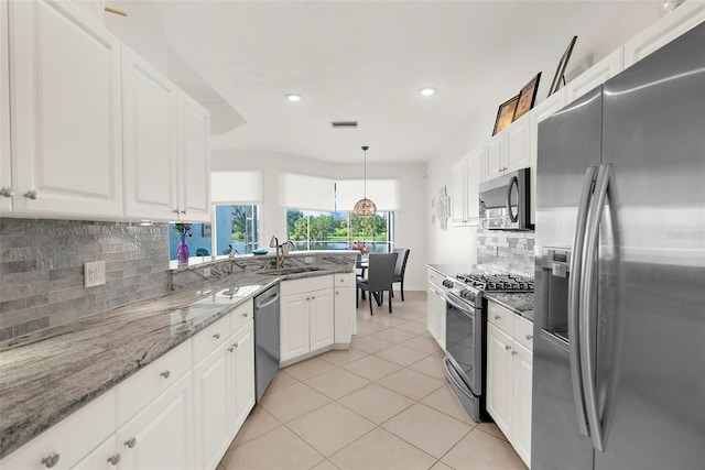 kitchen with pendant lighting, backsplash, white cabinets, sink, and stainless steel appliances