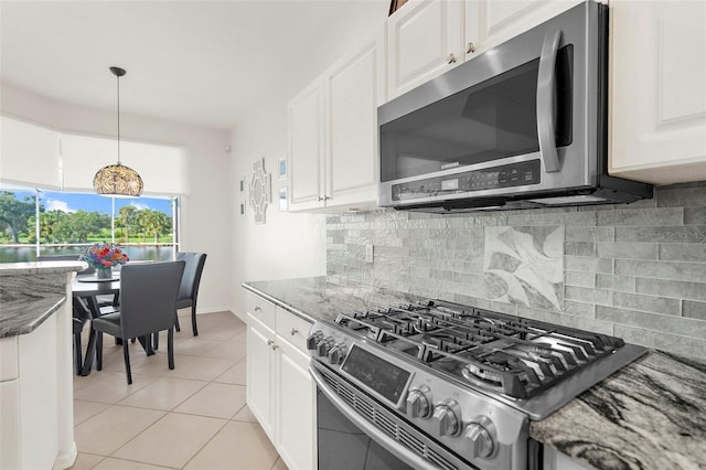 kitchen featuring dark stone countertops, white cabinetry, stainless steel appliances, and tasteful backsplash